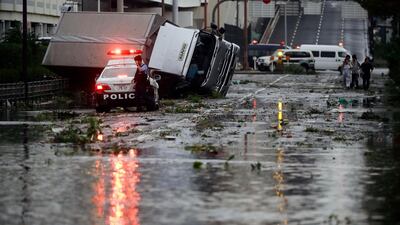 A police officer stands beside a flooded road following a powerful typhoon in Osaka, western Japan. Kyodo News via AP