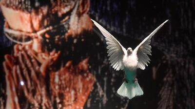 A poster photograph of George Michael is seen behind 'The Incomplete Truth' by Damien Hirst - a dove encased in a formaldehyde solution - ahead of the George Michael online auction. Reuters