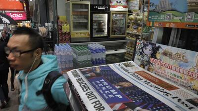 A man walks past a local newspaper reporting on the election victory of US President-elect Donald Trump in Hong Kong. Vincent Yu / AP Photo