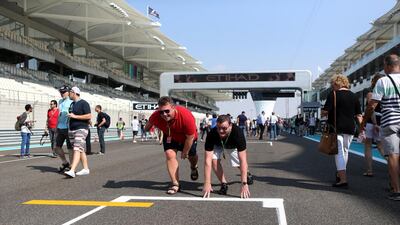 Spectators walk on the starting grid and pit lane ahead during an open period on Thursday at Yas Marina Circuit ahead of the Abu Dhabi Grand Prix on Sunday. Christopher Pike / The National