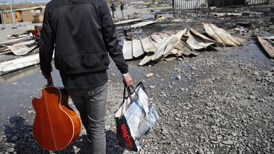 Ismael, a Kurdish migrant, carrying a guitar he salvaged from the burned remains of a migrant camp in the Dunkirk suburb of Grande-Synthe, northern France. Christophe Ena/AP Photo