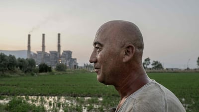 Turkish villager Okan Goktas, 44-years-old, cools off using the water irrigating his field in the late afternoon close to the coal-powered Yatagan power plant, at Yatagan, in Mugla province, southwest Turkey on August 16, 2023. The struggle to save the Akbelen forest in Mugla province, southwestern Turkey, on the Aegean Sea, from an expanding coal mining continues in the country’s southwest, as coal-powered thermal power plants continue to be part of Turkey’s development agenda. Although President Recep Tayyip Erdogan has said that the country aims to reach net zero emissions by 2053, Turkey has no goals for going beyond coal to generate electricity. (Photo by BULENT KILIC / AFP)