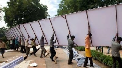 Indian workers carry a giant billboard as they work inside Shalimar Gardens, the venue for a concert by renowned Indian-born orchestra conductor Zubin Mehta, on the outskirts of Srinagar, India, on Tuesday. Dar Yasin / AP Photo