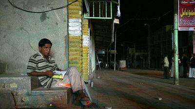 A young Iraqi studies in light from a diesel generator during a power blackout in Babil province.