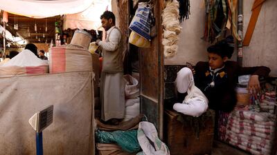 A Yemeni boy uses a smartphone as a vendor sells flour at a market in Sanaa, Yemen. EPA