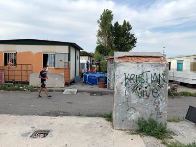 'A resident of the Salone Camp for Italy's Roma ethnic minority passes a static caravan; the camp, which is home to 400 inhabitants, lies 15km from the centre of Rome. Callum Paton / The National
