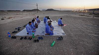 Labourers stop for maghrib prayers off of Sheikh Zayed road near the Jebel Ali Free Zone in Dubai. Jeff Topping / The National