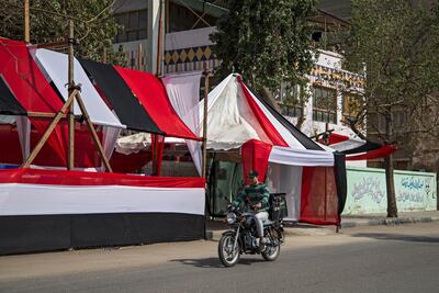 An Egyptian man drives a motorcycle in front of a school used as a polling station covered from outside by Egyptian flags, during the preparations for the upcoming referendum on constitutional amendments in Cairo. EPA