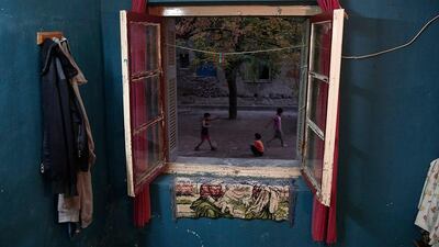 Children are seen from inside an apartment playing at an alley.