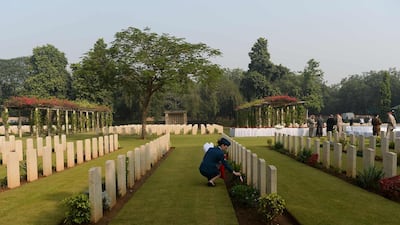 An Indian army officer puts flags next to a tombstone at Delhi War Cemetery in New Delhi. AFP