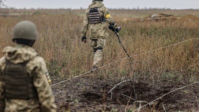 Ukrainian soldiers search for explosives at a recaptured area in the north of Kherson. EPA