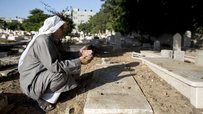 Hamed Abu Shabab prays over the grave of his son who was killed evacuating the wounded following an Israeli airstrike. Mahmud Hams / AFP / August 7