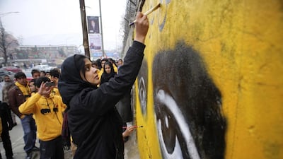 An Afghan social activist and member of Peace Street NGO paints a graffiti on a wall of the education ministry building in Kabul on March 8, 2014. Morteza Nikoubazl / Reuters