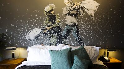 A Banksy wall painting showing Israeli border policeman and Palestinian in a pillow fight is seen in one of the rooms of the "The Walled Off Hotel" in the West Bank city of Bethlehem. Dusan Vranic / AP Photo