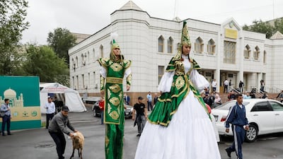 Artists walk past as a man leads a sheep to slaughter in Almaty. Reuters