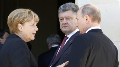 The German chancellor Angela Merkel talks to Russian president Vladimir Putin, right, as Ukraine’s president-elect Petro Poroshenko looks on after a group photo for the 70th anniversary of the D-Day landings at Benouville Castle, France, on June 6, 2014. Regis Duvignau / Reuters