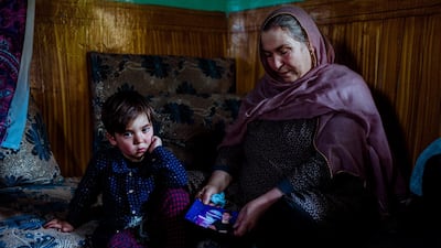 Fawzia, Tooryalai's mother, displays a photo of Tooryalai in a room at their home as his son Kawsar sits nearby. Ivan Flores / The National