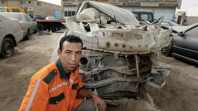 Car-crash recovery driver Wajdi Mubarak beside a wreck at Al Sahraa Recovery Services in Mussafah Industrial Area.