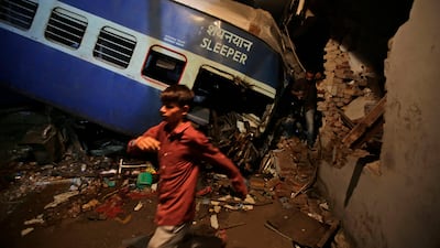 An Indian boy walks past the upturned coaches of the Kalinga-Utkal Express after an accident near Khatauli, in the northern Indian state of Uttar Pradesh, India on Sunday. Altaf Qadri / The Associated Press
