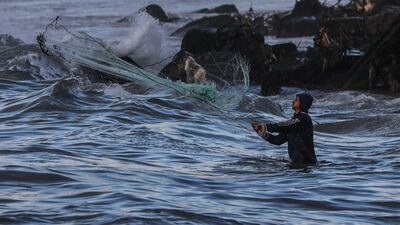 A Palestinian refugee throw his net in the beach during a cold weather at Al-Shati refugee camp in Gaza City. EPA