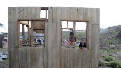 Children look from a window of a roofless house, destroyed at the height of Typhoon Bopha in the coastal town of Boston in the southern Philippines.