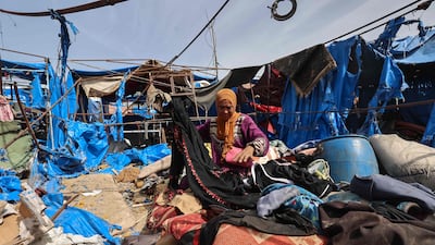 A Palestinian woman gathers her belongings inside her damaged shelter following overnight Israeli air strikes in the central Gaza Strip. AFP