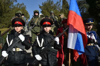 Students of a military school and Russian soldiers in Crimea stand in front of plaques with the names of Russian troops who died during fighting in Ukraine. AP