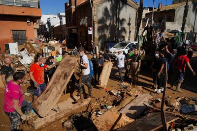 People clear mud and debris from streets of the town of Alfafar, in Valencia, on Saturday. AFP
