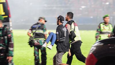 People help carry an injured spectator after a football match between Arema FC and Persebaya on October 1. AFP