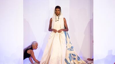 Helen Storey, left, adjusts the hem of her Dress of our Times at the show in London. Simon Armstrong