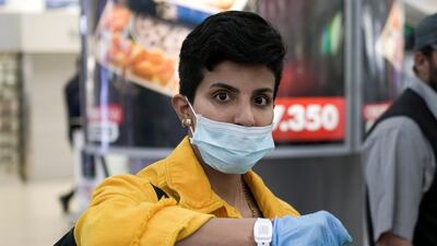 A Kuwaiti woman wearing a protective face mask poses as she shows her quarantine tracking bracelet upon her arrival from Amman to Kuwait Airport. Reuters