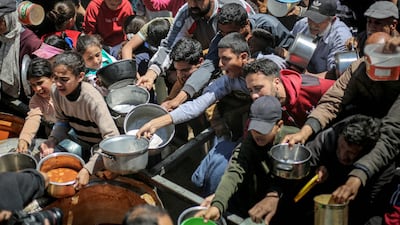 Displaced Palestinians receive food from a charity kitchen at the Nuseirat refugee camp in the central Gaza. AFP