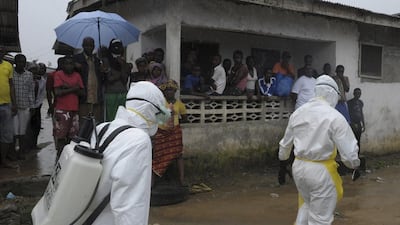 Health workers wearing protective clothing prepare to carry an abandoned dead body with Ebola symptoms in Monrovia . Reuters / 2Tango