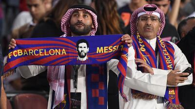A Barcelona fan holds a scarf depicting Messi. AFP