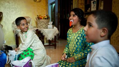 Awashi Al Suwaidi, 12, centre, jokes around with her family after opening her two bags filled with sweets and crisps. Every mid-Shaaban – 15 days before the holy month of Ramadan – Emirati children celebrate Haq Al Lailah (for this night) by gathering???
