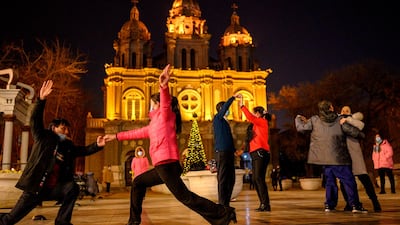 People wearing face masks dance in front of St. Joseph's Church in Beijing. AFP