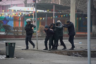 A police officer escorts a group of detained protesters in Almaty, Kazakhstan, Thursday, Jan. 6, 2022. Vladimir Tretyakov/NUR. KZ via AP