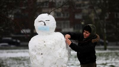 A boy works on a mask-clad snowman on Primrose hill during snowfall in London, Britain. Reuters