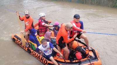 Residents leave their homes next to a swollen river in Cagayan de Oro, Mindanao island, amid heavy rains brought about by Typhoon Rai. Photo: AFP