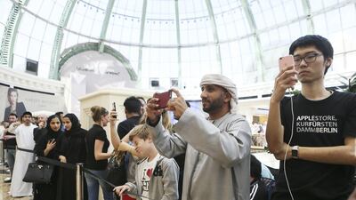 Customers take pictures ahead of the opening. To the right is the first customer to step foot inside the store, while the second was an Emirati who queued for 26 hours. Sarah Dea / The National