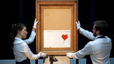 Staff from Sotheby's auctioneers reposition Banksy’s'Love is in the Bin', which is now half-shredded Reuters