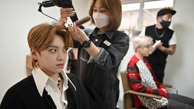 Member Jang Jun-ho, left, having his hair done at a beauty salon in Seoul ahead of a promotional shoot. AFP