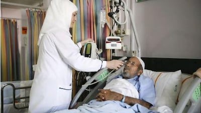 November 29, 2011, Dubai, UAE: Right to left: Hind Mahmoud Abdulla Younes,is a nurse in the Trauma center of Rashid hospital. She takes care of multiple patients in severe pain, 12 hours at a time. Here she takes the temperature of Mohammed Nasser who suffers from a cervical disc prolapse. Lee Hoagland/The National