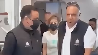 Alia Hassouni, former employee of the Wasit Health Directorate, centre, disembarks from a plane. SNA