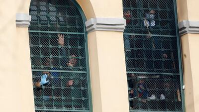 Inmates stand behind bars at the San Vittore prison as protests broke out following restrictions that were imposed on family visits to prevent coronavirus transmissions, in Milan, Italy. AP Photo