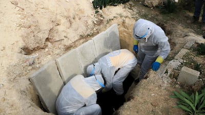 Three White Helmet volunteers gently place the body of Ghada Ismael inside a grave in northwestern Syria’s Salqeen cemetery.