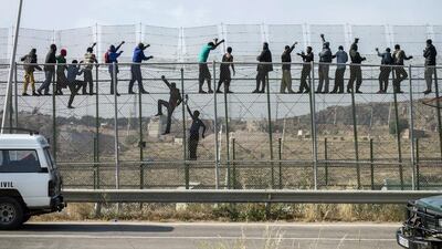 African migrants climb a border fence covered in razor wire during their latest attempt to cross into Spanish territory between Morocco and Spain's north African enclave. Photo: Jesus Blanco / Reuters