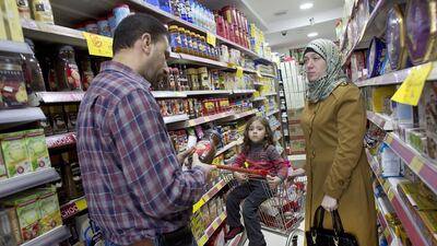 Ali Hindy checks the label on a jar of instant coffee as he shops with his family in a supermarket in Ramallah that is complying with the boycott of the six Israeli companies. Heidi Levine For The National.