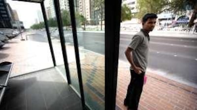 A commuter waits for his bus at a non-functioning air-conditioned bus stop on Airport Road.
