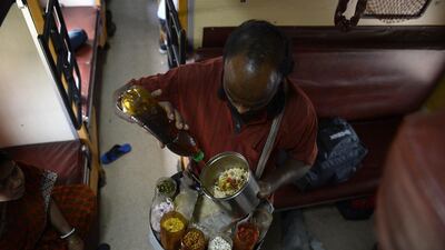 An Indian vendor sells snacks on board the Kalka Mail train.